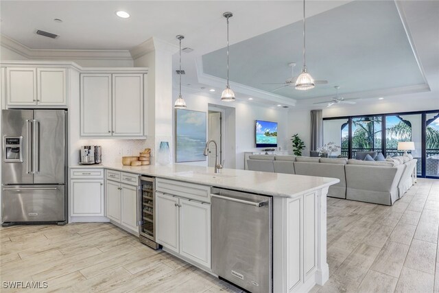 kitchen with appliances with stainless steel finishes, ceiling fan, a raised ceiling, and wine cooler