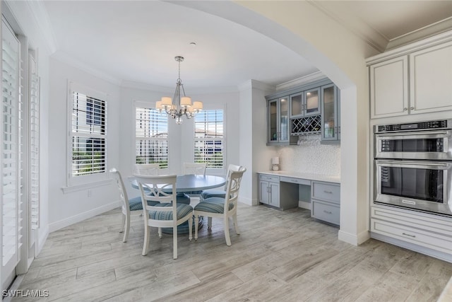 dining space featuring light hardwood / wood-style floors, crown molding, and a chandelier