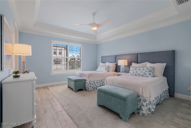 bedroom with ornamental molding, ceiling fan, a raised ceiling, and light hardwood / wood-style floors