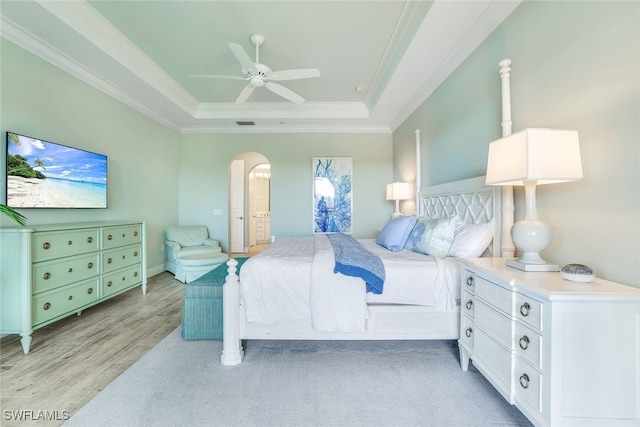 bedroom featuring crown molding, ceiling fan, light wood-type flooring, and a tray ceiling