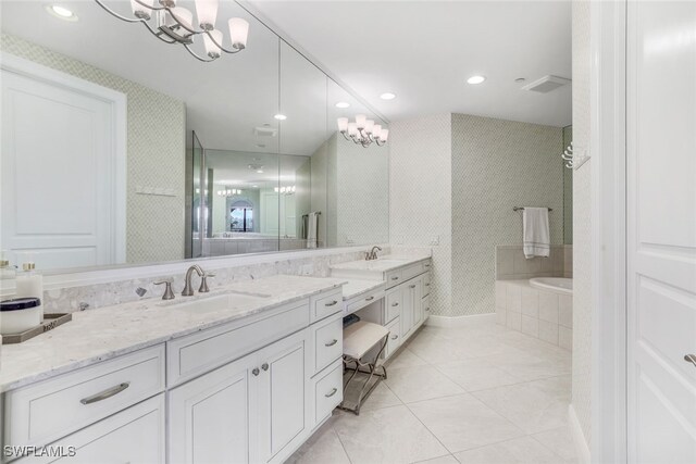 bathroom with tile patterned floors, a chandelier, tiled bath, and dual bowl vanity