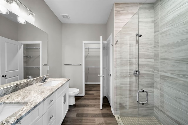 bathroom with hardwood / wood-style flooring, a shower with door, toilet, and dual bowl vanity