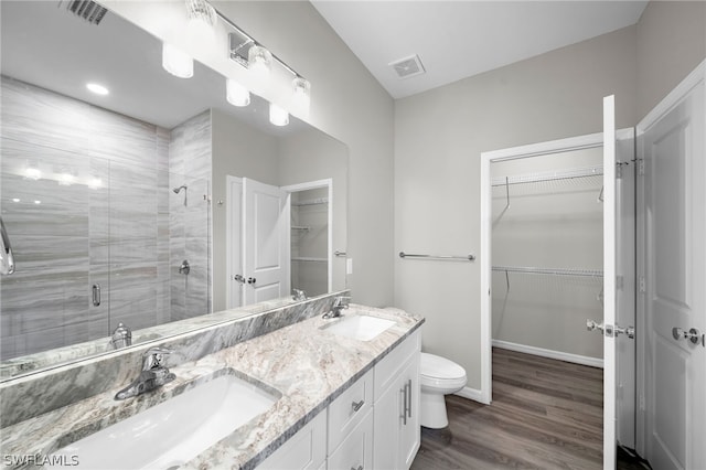 bathroom with toilet, dual vanity, hardwood / wood-style floors, and an enclosed shower