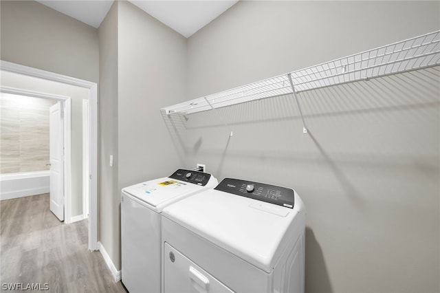 laundry room featuring washing machine and dryer and light hardwood / wood-style floors