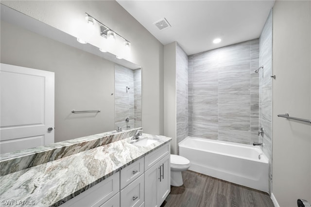 full bathroom with hardwood / wood-style flooring, tiled shower / bath combo, toilet, and vanity