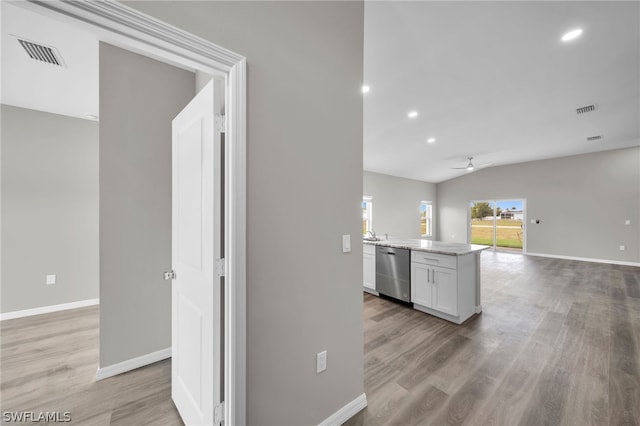 kitchen with white cabinets, light hardwood / wood-style floors, stainless steel dishwasher, lofted ceiling, and ceiling fan