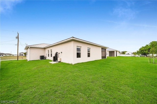 rear view of property featuring cooling unit and a lawn