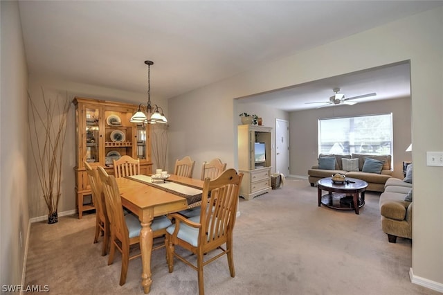 carpeted dining room with ceiling fan with notable chandelier