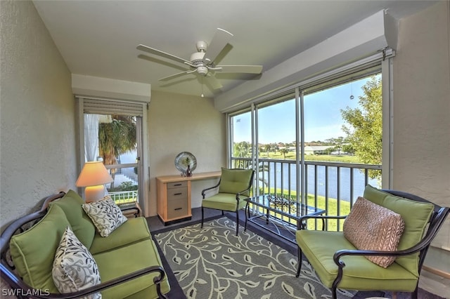 sunroom with plenty of natural light, a water view, and ceiling fan