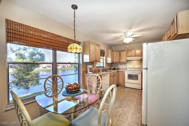 tiled dining room featuring sink, a water view, and ceiling fan