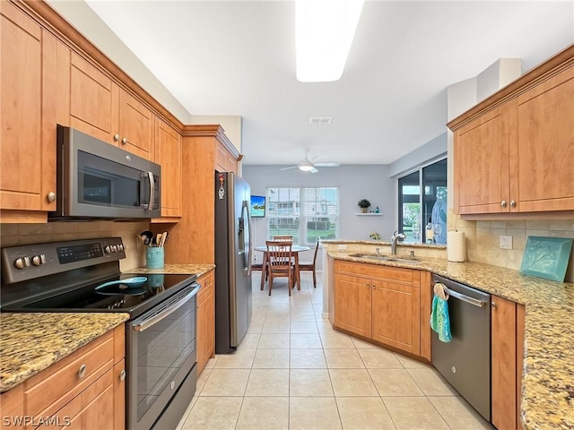 kitchen featuring appliances with stainless steel finishes, sink, decorative backsplash, light tile patterned floors, and light stone countertops