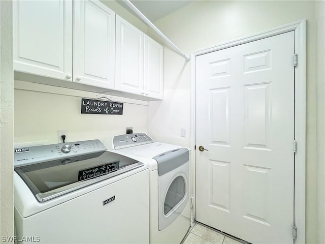 clothes washing area with light tile patterned floors, cabinets, and washing machine and clothes dryer