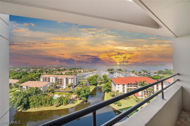 balcony at dusk featuring a water view