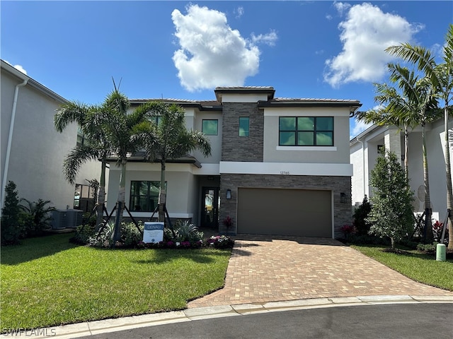 view of front of house with a front yard, a garage, and central AC unit