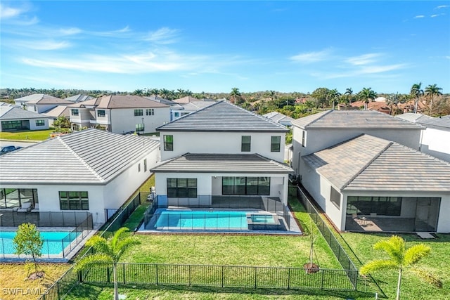 rear view of house with a fenced in pool and a lawn