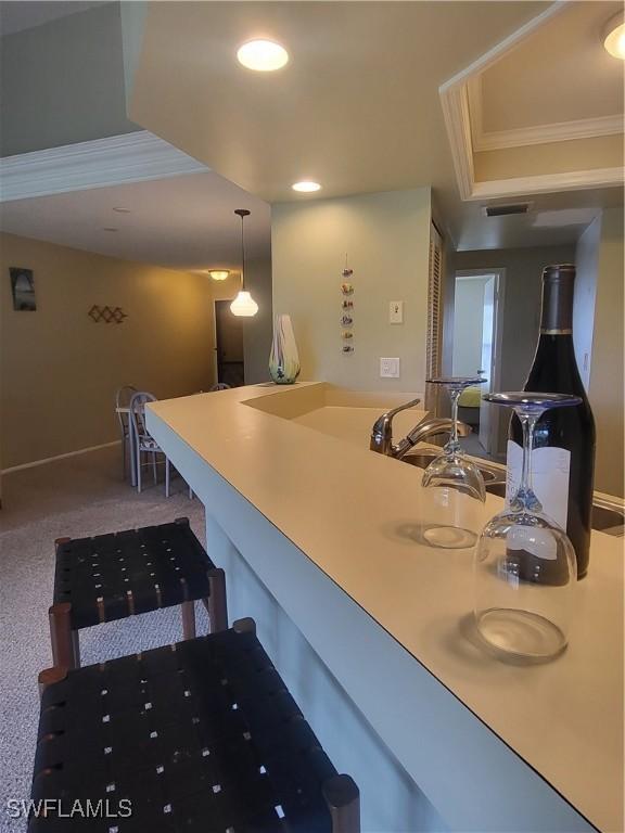 kitchen featuring carpet floors, sink, crown molding, and a raised ceiling