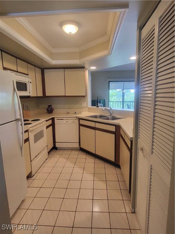 kitchen with a raised ceiling, sink, white appliances, light tile patterned flooring, and ornamental molding