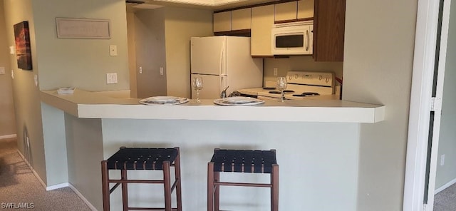 kitchen with a peninsula, white appliances, baseboards, and light countertops