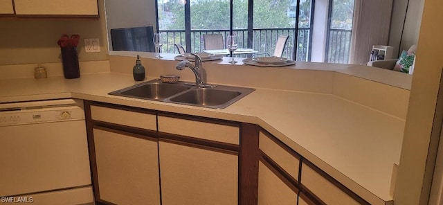 kitchen featuring white dishwasher, light countertops, and a sink