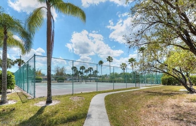 view of tennis court featuring a yard and fence