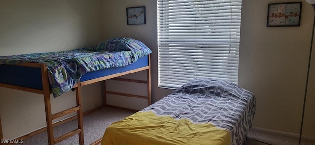 carpeted bedroom featuring multiple windows and baseboards