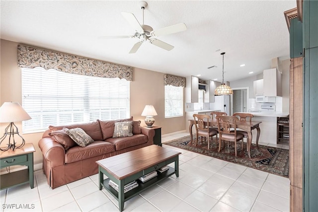 tiled living room featuring ceiling fan, plenty of natural light, and vaulted ceiling