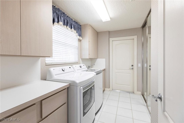 laundry room with cabinets, a textured ceiling, washer and clothes dryer, and light tile patterned flooring