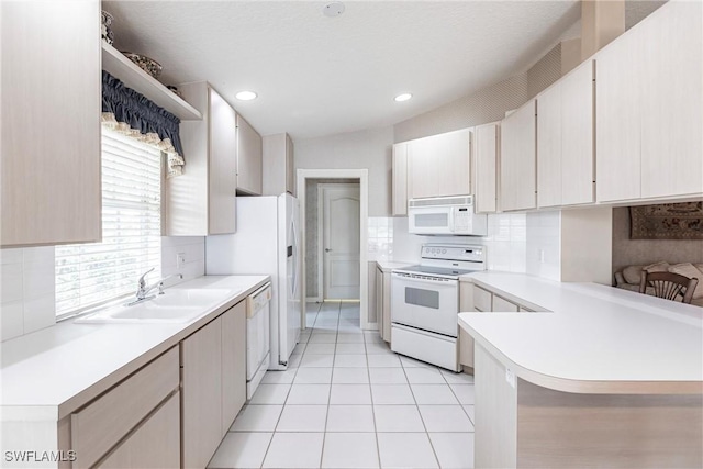 kitchen featuring lofted ceiling, white appliances, sink, light tile patterned floors, and kitchen peninsula