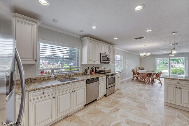 kitchen with sink, appliances with stainless steel finishes, hanging light fixtures, ornamental molding, and white cabinets