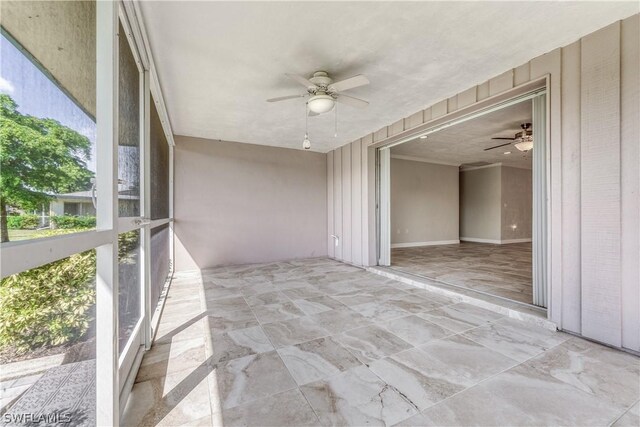 unfurnished sunroom featuring ceiling fan