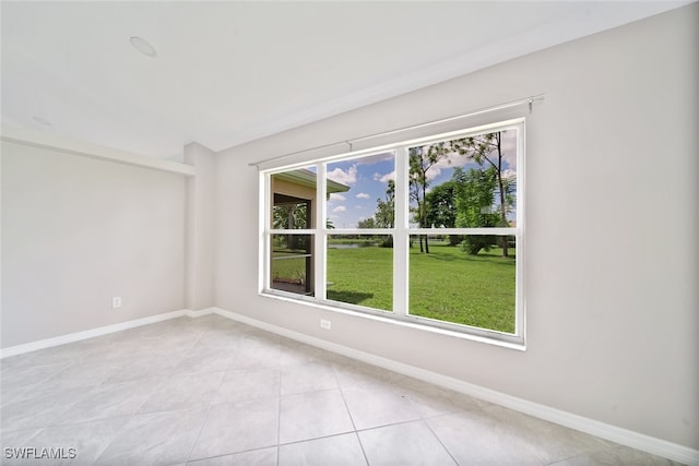 spare room featuring light tile patterned flooring and a healthy amount of sunlight