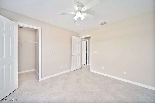 unfurnished bedroom with ceiling fan, a closet, a walk in closet, and light tile patterned floors