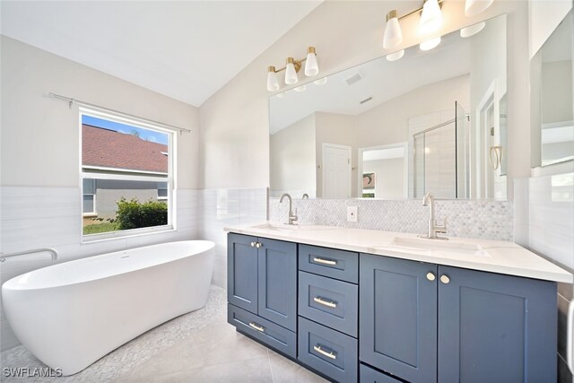 bathroom featuring decorative backsplash, tile patterned floors, double sink vanity, tile walls, and vaulted ceiling