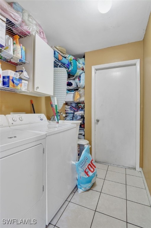 laundry area featuring cabinets, light tile patterned flooring, and washing machine and clothes dryer