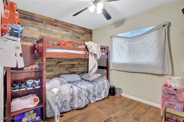 bedroom with wood walls, ceiling fan, and hardwood / wood-style floors