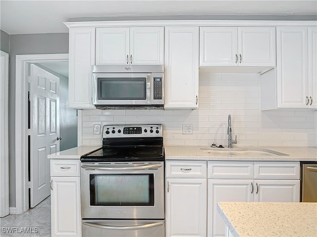 kitchen with white cabinetry, light stone countertops, light tile patterned floors, stainless steel appliances, and sink