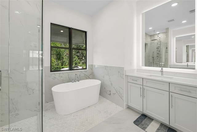 bathroom with shower with separate bathtub, tile walls, and vanity