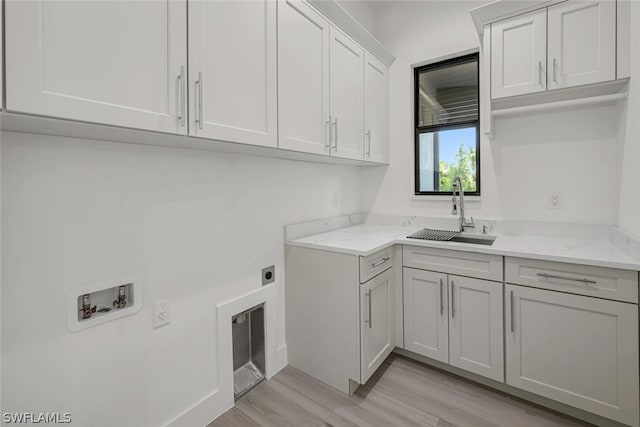 clothes washing area featuring sink, cabinets, light wood-type flooring, hookup for a washing machine, and electric dryer hookup