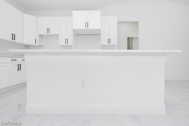 kitchen featuring light tile patterned floors, white cabinets, vaulted ceiling, and a kitchen island