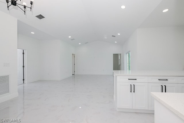 tiled empty room featuring lofted ceiling