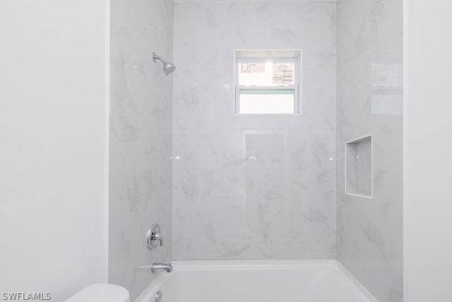 bathroom with toilet and tiled shower / bath