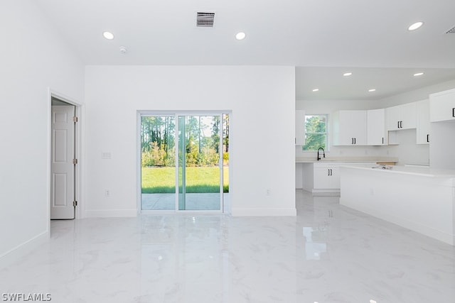 unfurnished living room featuring a healthy amount of sunlight, sink, and light tile patterned floors