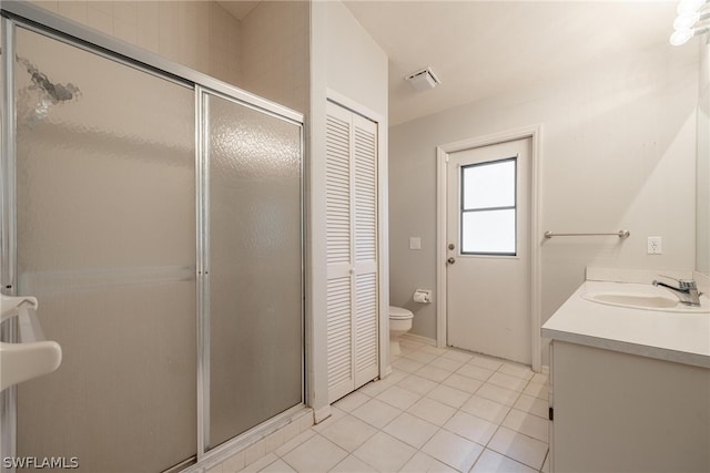 bathroom with vanity, walk in shower, tile patterned flooring, and toilet