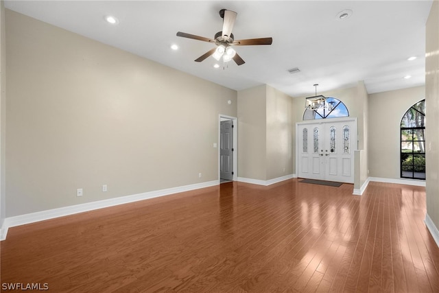 unfurnished room featuring wood-type flooring, ceiling fan with notable chandelier, and lofted ceiling