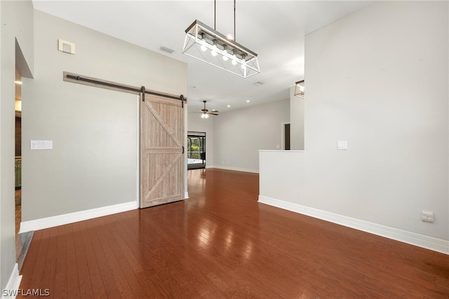 spare room with ceiling fan, dark hardwood / wood-style flooring, and a barn door