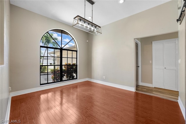 unfurnished room with wood-type flooring and an inviting chandelier