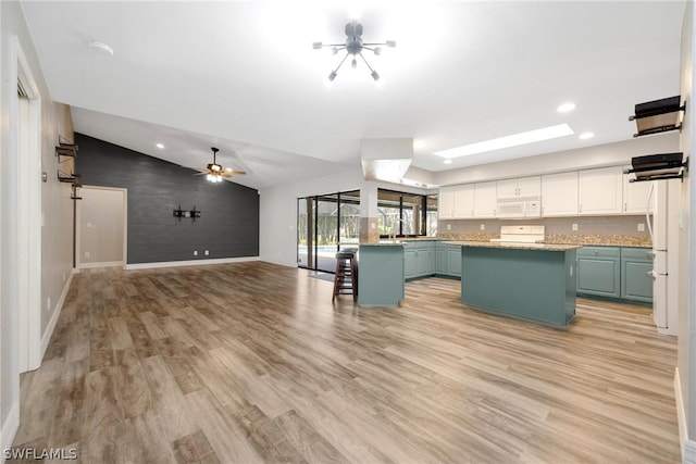 kitchen with white cabinetry, ceiling fan, vaulted ceiling, a kitchen island, and light hardwood / wood-style floors