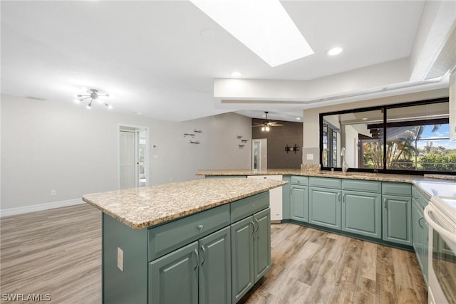 kitchen with a kitchen island, green cabinets, range, and light hardwood / wood-style flooring