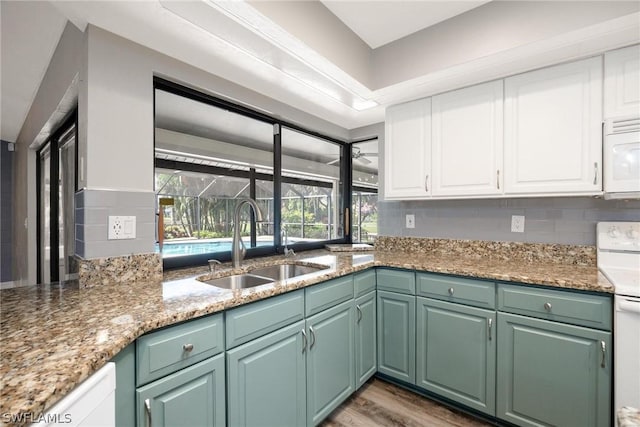 kitchen with sink, backsplash, white cabinets, and white appliances