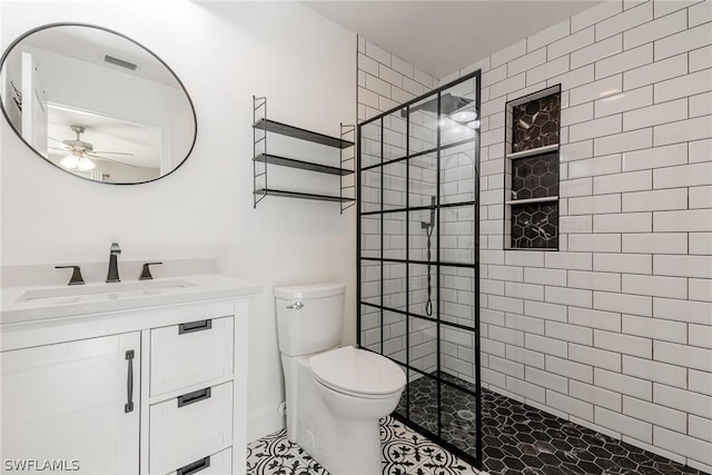 bathroom with ceiling fan, a tile shower, vanity, tile patterned floors, and toilet